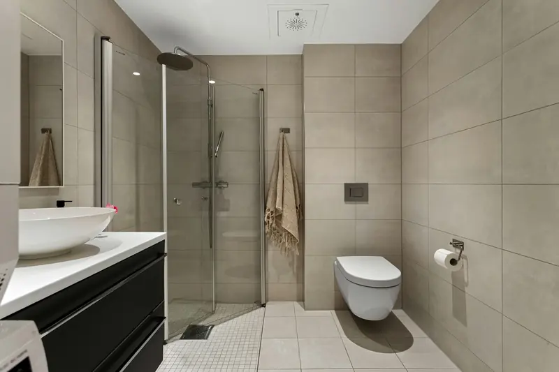 Modernes Bad mit bodengleicher Dusche, Glaswand, großen Fliesen und Hänge-WC