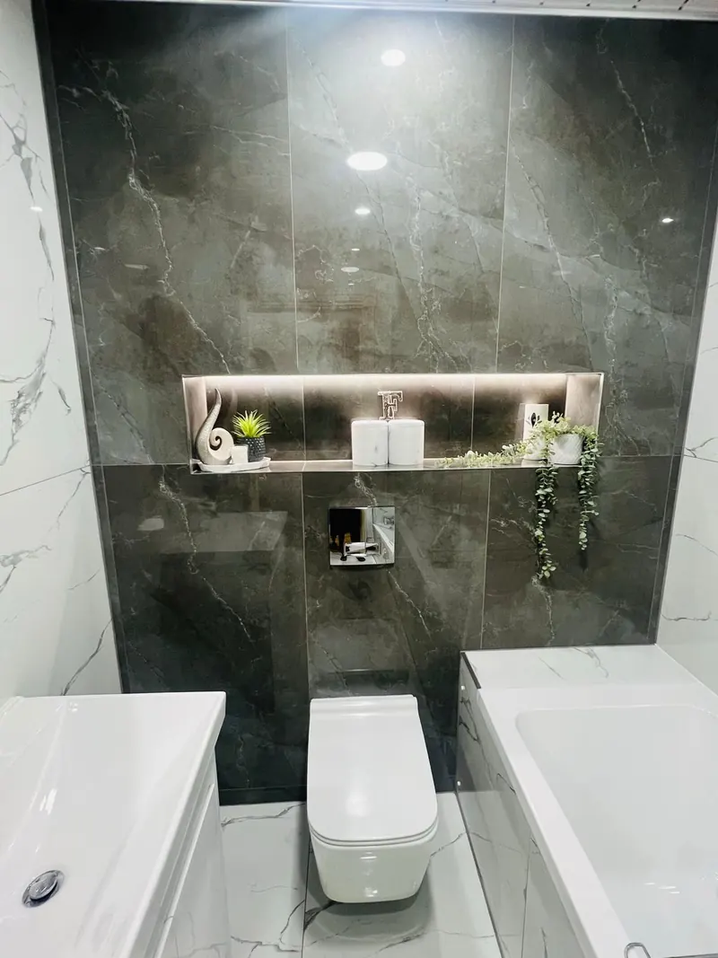 WC mit beleuchteter Wandnische und dunklen Fliesen in Marmoroptik