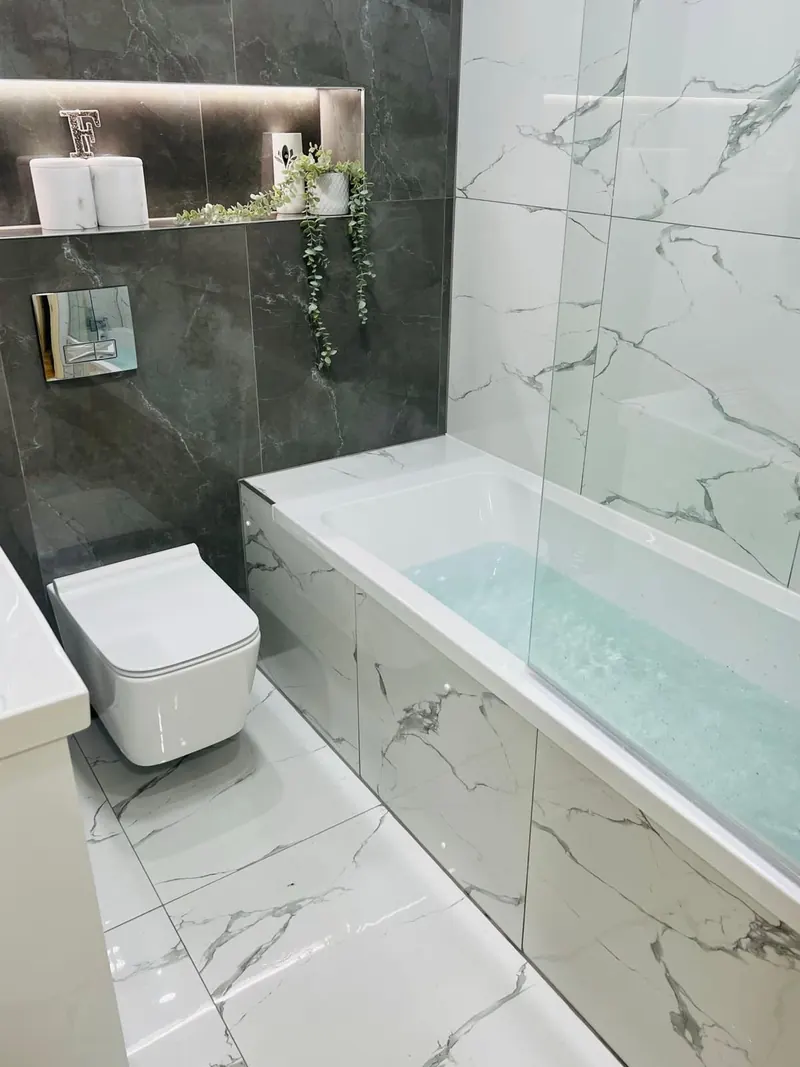 Bad mit Badewanne, Glasabtrennung, Hänge-WC und Fliesen in Marmoroptik