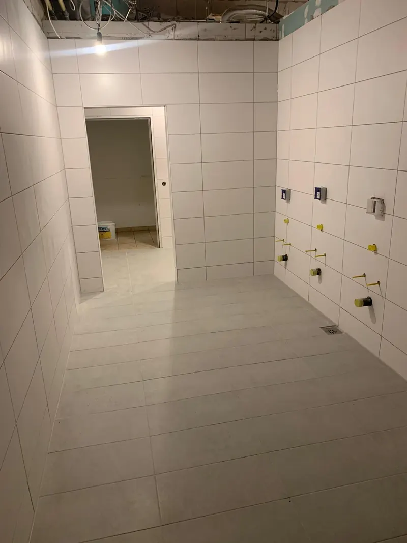 Weiß gefliester Sanitärraum mit vorbereiteten Anschlüssen