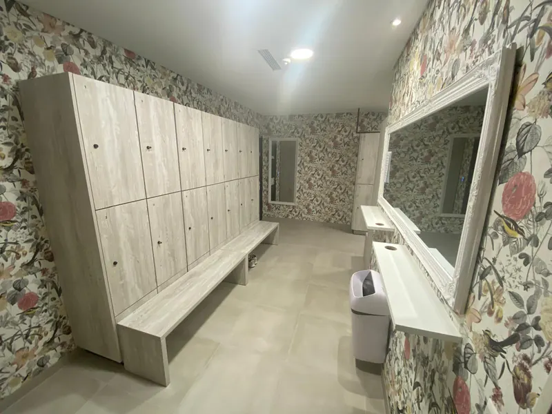 Umkleide mit Spinden, Sitzbank, Spiegel und gemusterter Wand